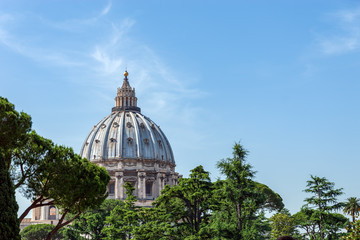St. Peter's Basilica dome surrounded by trees, as seen from Vatican Gardens - Vatican City, Rome, Italy.