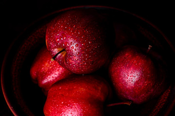 Fresh juicy red apple with droplets of water against dark background