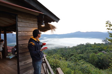 Man holding a coffee cup and views of Phu Lanka in the morning in Phayao, Thailand