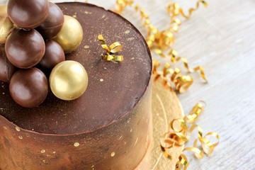 Chocolate birthday cake with gold decorations. Holiday concept.
