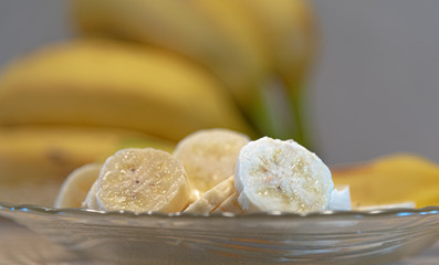 Bananas cut and served on a plate and defocused banana fruits in the background