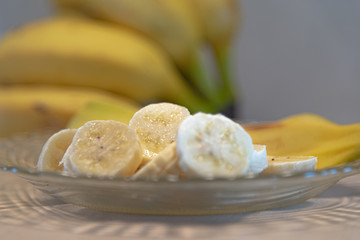 Bananas cut and served on a plate and defocused banana fruits in the background
