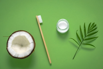 top view bamboo eco friendly tooth brush, tooth paste jar , coconuts and green tropical leaves, homemade toothpaste and dental care concept