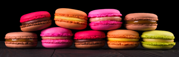 Stack of french colorful macaroons in row isolated on black background