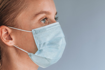 A girl in a medical mask on a gray background. copy space