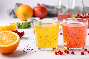 Tropical orange and pomegranate juice with basil seeds or falooda seeds or tukmaria in glasses and bottles on white background, Closeup