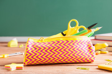 Pencil bag with stationery on desk in classroom