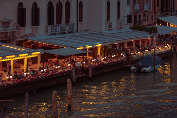 Fototapeta na wymiar Venice, Italy - May 25, 2019: view of restaurant at city quay summer time