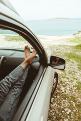 Fototapeta premium woman legs at car dashboard sea on background