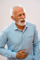 Portrait of senior man who is having pain in stomach.