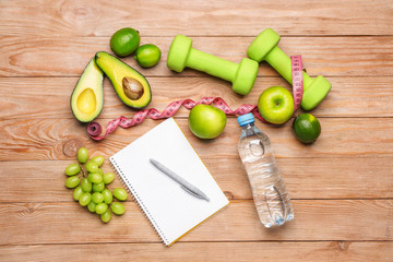Notebook with measuring tape and healthy products on table