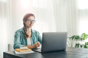 Woman sits in front of lap top. 