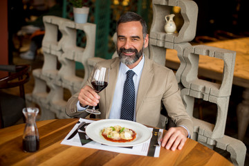 Handsome mature man drinking red wine during lunch