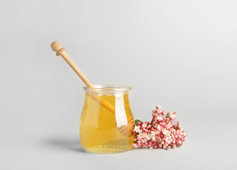 Jar of sweet honey on light background