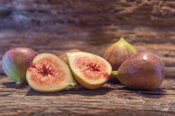 Fig fruits (Ficus carica) fresh and in halves on wooden surface