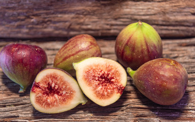 Fig fruits (Ficus carica) fresh and in halves on wooden surface