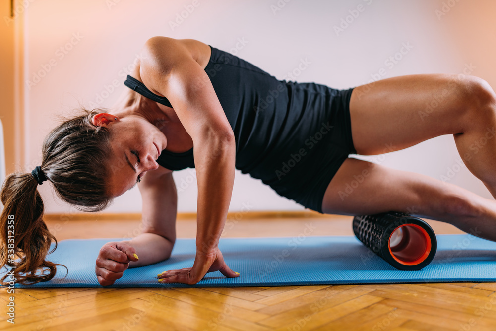 Wall mural woman massaging legs with foam roller