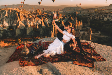 Couple having romantic moments in Cappadocia love valley. Hundreds of hot air balloons in the sky. Happy couple. Valentine's day.