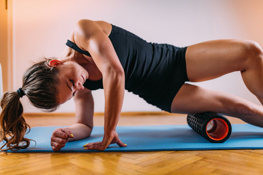 Woman Massaging Legs with Foam Roller