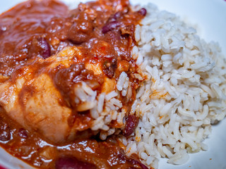 Close up of sweet and spicy South American style chicken mole and healthy brown wholegrain rice dinner in a red serving bowl