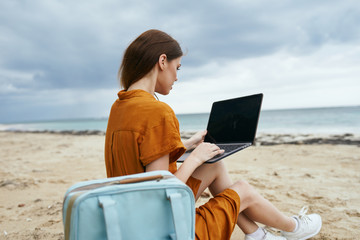 woman with laptop on the beach