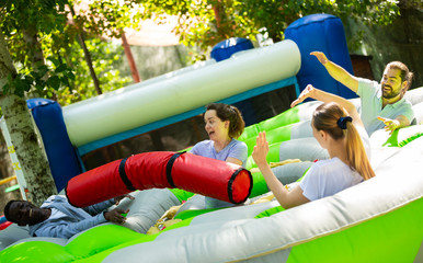 Fototapeta na wymiar Funny friends playing on an inflatable trampoline in an amusement park