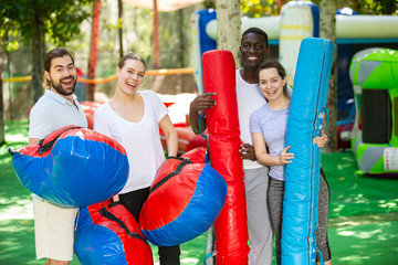 Fototapeta na wymiar Portrait of happy friends with inflatable logs and pillows at an amusement park