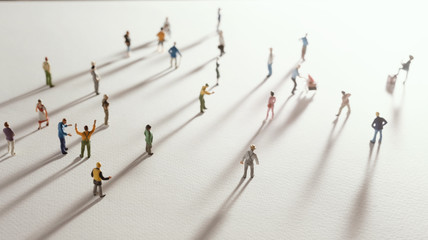 Top view of people (miniature toys) with long shadows keep distance away in public during sunrise...