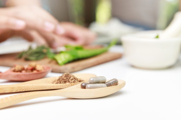 Herbal medicine preparation with fresh herbs and dried flowers, aromatherapy essential oil and mortar with pestle used in natural alternative remedies on white table.