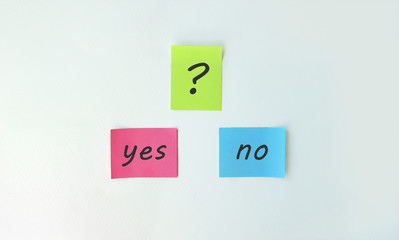 Photo two stickers with the phrase yes or no and with a sticker with a question mark on a white background.
