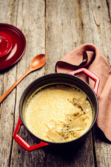 Creamy Polenta with baked onion and cheese in cast iron pot on rustic wooden background. Italian food. Selective focus. Toned image