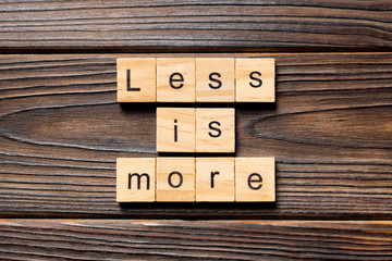less is more word written on wood block. less is more text on table, concept