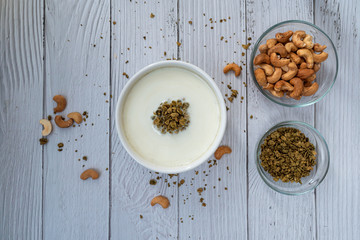 Bowl of cereal matcha oat granola with oat milk, cashew nuts on white wood  Background. vegan food