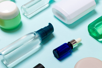 Top view of cosmetic products in different jars and bottles on blue background. Close-up of containers with copy space