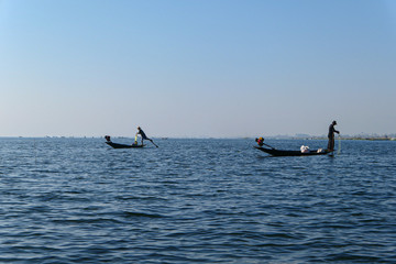 Aisan fisherman on the wooden boat on the lake. Men fishing on the blue river.