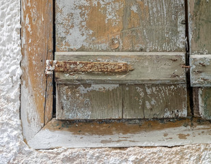 partial view of old weathered window shutters on white washed wall