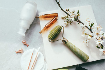 Dermaroller and serum next to an anti aging face cream Beauty industry  Dermaroller for medical micro needling therapy Derma roller mesoroller for mesotherapy on a light background near flowers