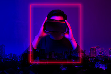 Asian man wearing the virtual reality goggles blue and magenta neon light scene