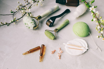 Dermaroller and serum next to an anti aging face cream Beauty industry  Dermaroller for medical micro needling therapy Derma roller mesoroller for mesotherapy on a light background near flowers