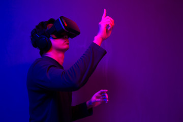 Asian man wearing the virtual reality goggles blue and magenta neon light scene