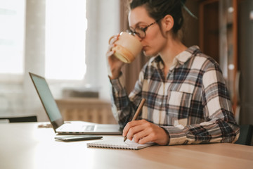 Girl making notes and drinking tea at home
