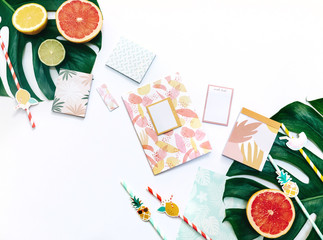 Creative flat lay with Exotic tropical monstera palm leaf and home office stationery on minimal background with summer fruits.
