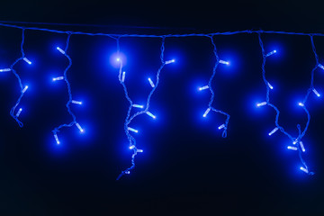 Blue garland. New Year's lights. Festive lighting. LED garland on a black background.