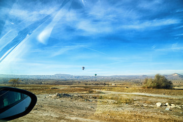 View from car window on the road and strange landscape with a valley, mountains and blue sky with clouds. Landscape through windscreen in Cappadocia in Turkey