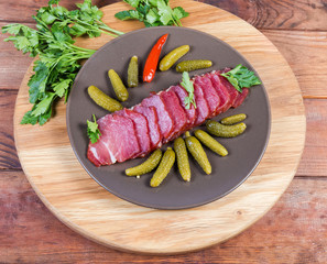 Dried-smoked pork neck with pickled gherkins, top view