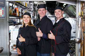 Obraz premium Cheerful cooks at restaurant kitchen