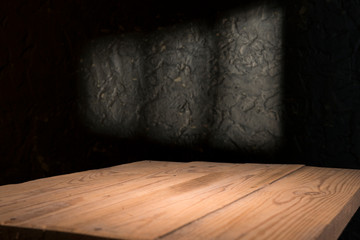 Old wood table with blurred concrete block wall in dark room background.