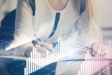 Double exposure of hands making notes with forex chart huds. Stock market concept.