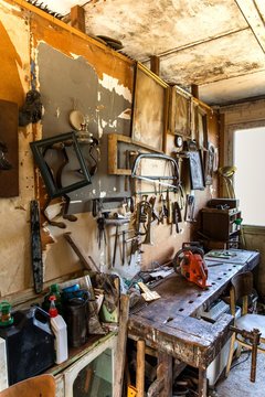 Old carpentry tools in home workshop. Repair of agricultural machinery. Old planers and drills on workshop wall.