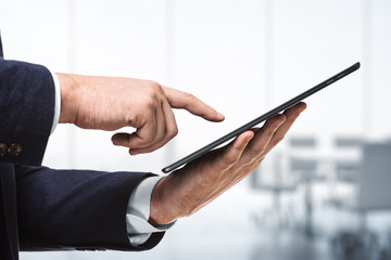 Businessman hand clicks on the screen of a digital tablet in conference room, close up. Internet Work Concept